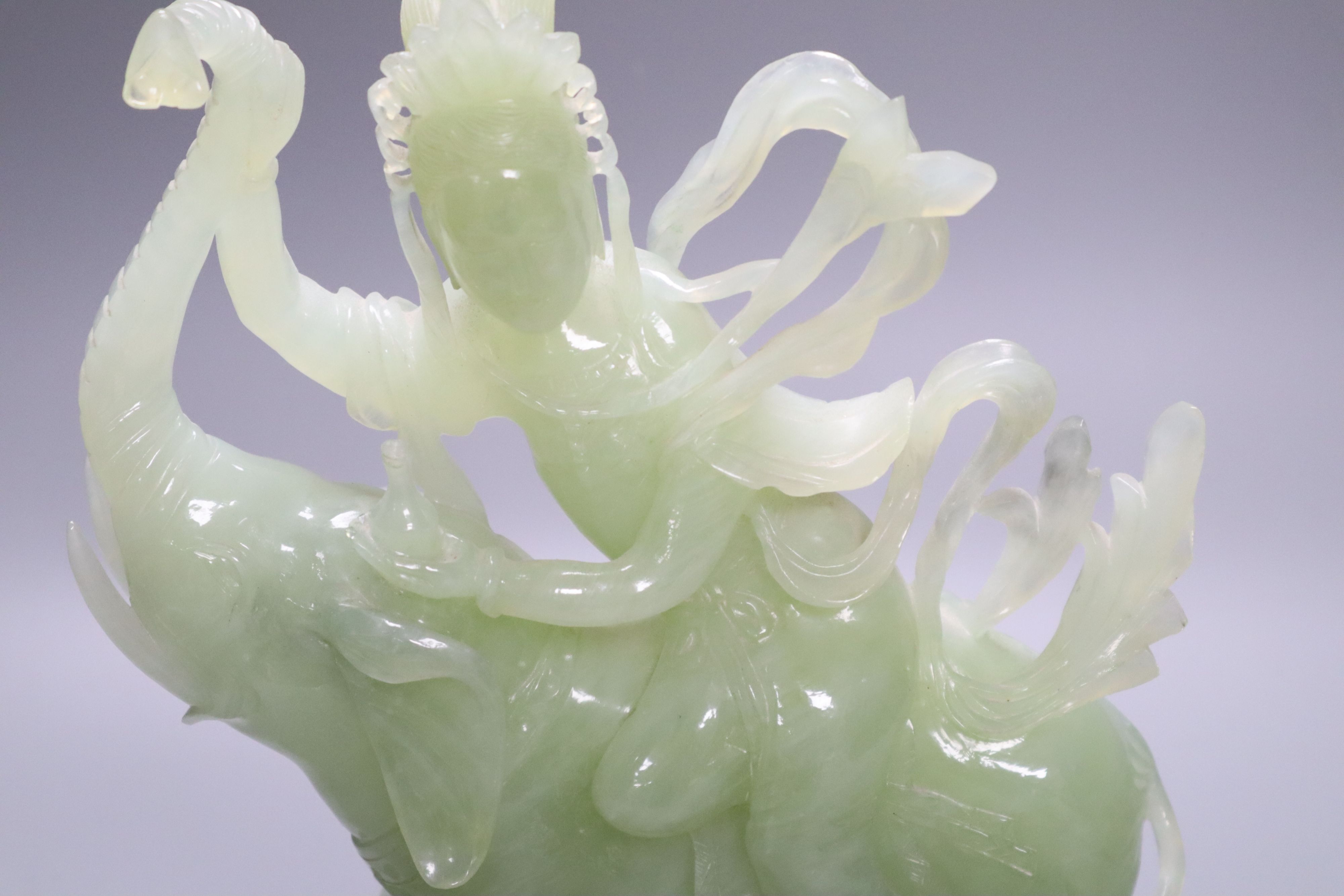 A Chinese bowenite jade group of Guanyin riding on elephant, 27cm high, wood stand